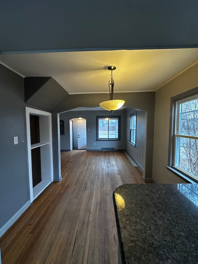 interior space featuring arched walkways, visible vents, baseboards, hardwood / wood-style floors, and crown molding