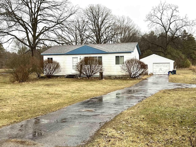 view of front of house with a garage, an outbuilding, a shingled roof, and a front lawn