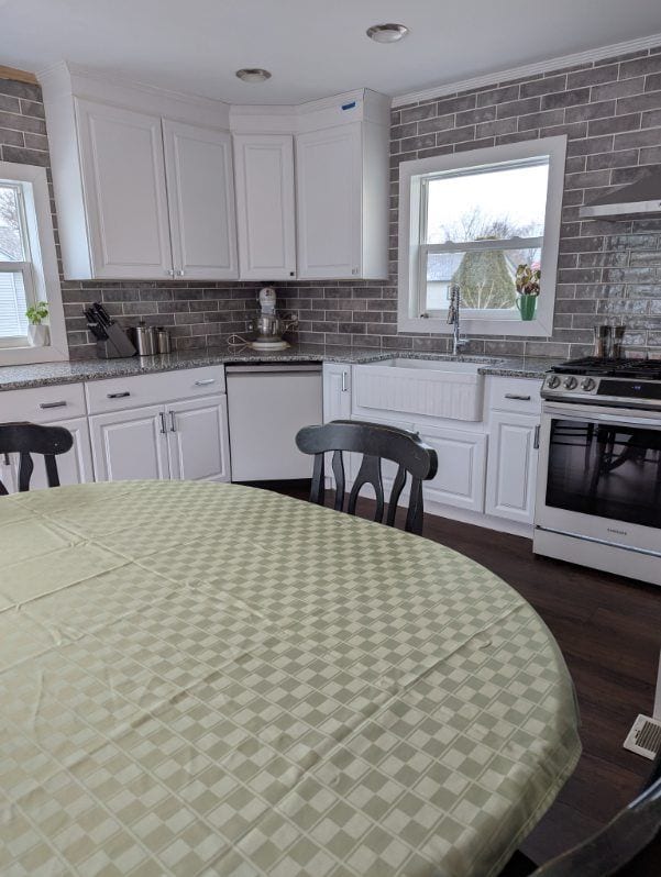 kitchen featuring tasteful backsplash, white dishwasher, gas range, and white cabinetry