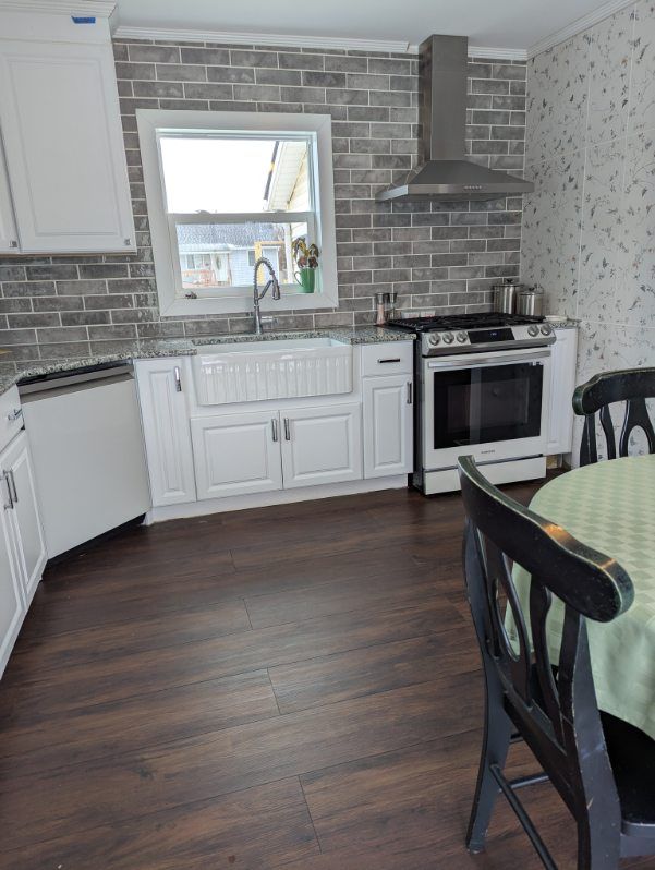 kitchen with decorative backsplash, dishwasher, wall chimney range hood, stainless steel range with gas cooktop, and a sink