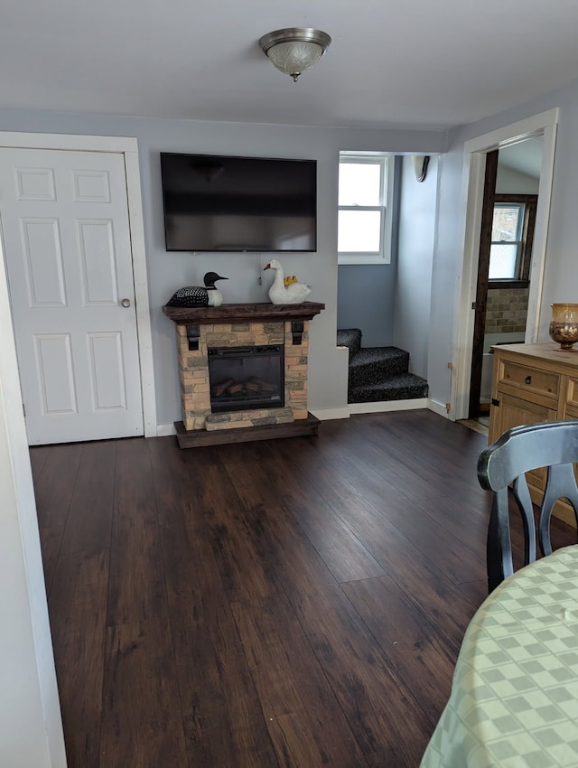 living room featuring dark wood-type flooring, a fireplace, stairway, and baseboards