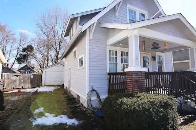 view of front of property featuring a garage, covered porch, fence, and an outdoor structure