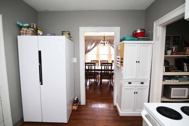 kitchen featuring a textured ceiling, white appliances, dark wood-type flooring, and an inviting chandelier