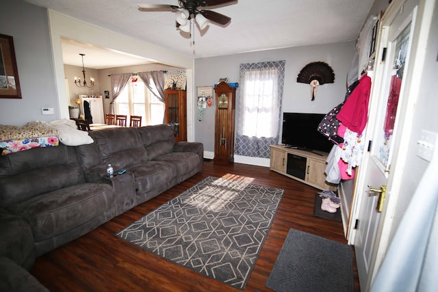 living area featuring ceiling fan with notable chandelier, a healthy amount of sunlight, baseboards, and wood finished floors