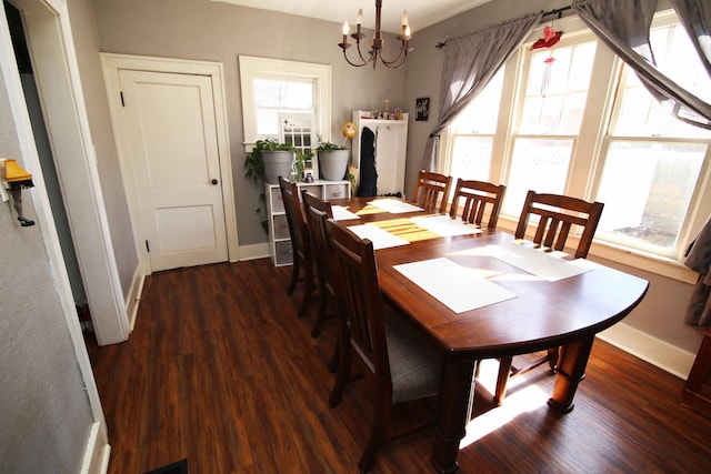 dining space with baseboards, wood finished floors, and a notable chandelier