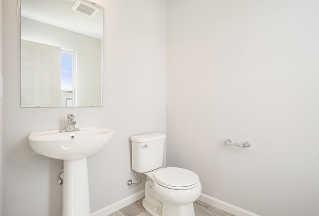 bathroom with wood finished floors, baseboards, visible vents, a sink, and toilet