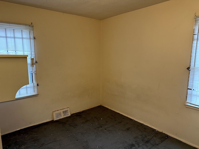 unfurnished room featuring dark colored carpet and visible vents