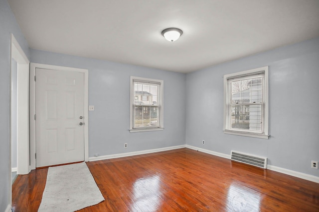 spare room featuring baseboards, visible vents, and dark wood finished floors