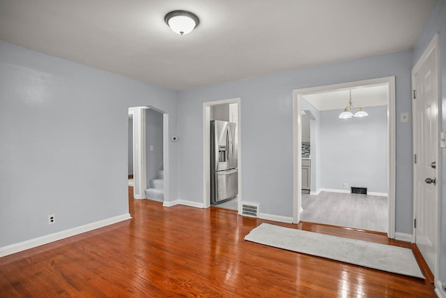 spare room with wood-type flooring, visible vents, arched walkways, and baseboards