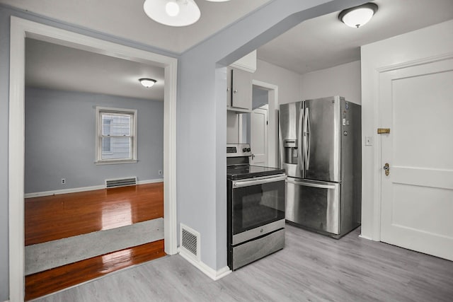 kitchen featuring appliances with stainless steel finishes, visible vents, and light wood-style flooring