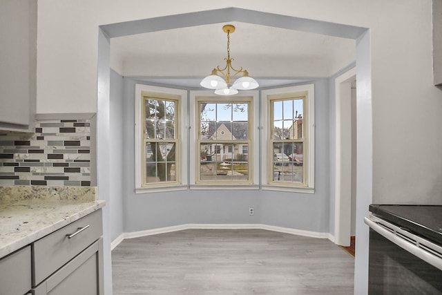 dining room featuring light wood-style floors, a notable chandelier, and baseboards