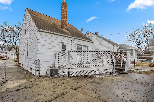 back of house with a chimney, a shingled roof, central AC, fence, and a deck