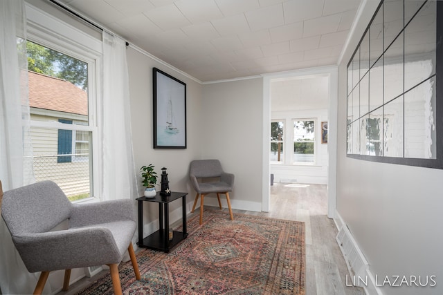 sitting room with ornamental molding, baseboards, and wood finished floors