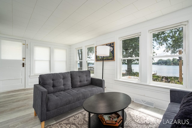 living room featuring light wood-type flooring, a water view, and visible vents