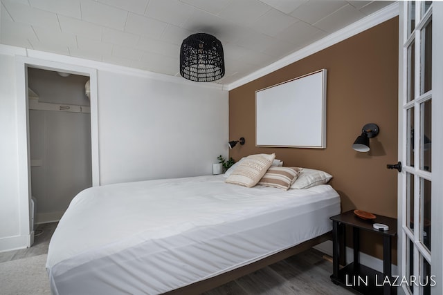 bedroom featuring ornamental molding, baseboards, and wood finished floors