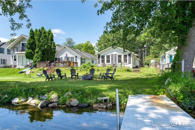 back of property with an outdoor fire pit, a lawn, and a wooden deck