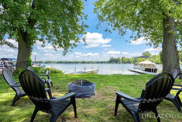 view of yard featuring a water view, a fire pit, and a boat dock