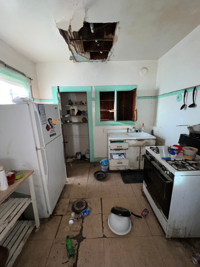 3674 Mount Elliott St, Detroit, MI 48207 - kitchen featuring light countertops, light tile patterned floors, and white appliances