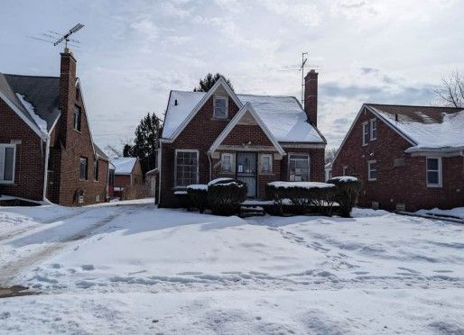 tudor home with a chimney and brick siding