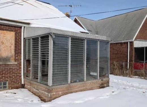 snow covered structure with a sunroom