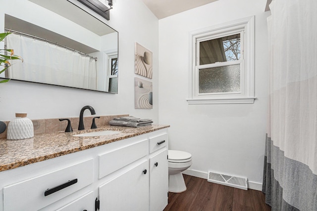 full bath featuring toilet, wood finished floors, vanity, visible vents, and baseboards