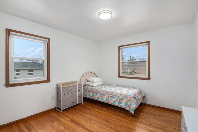 bedroom with light wood-type flooring, multiple windows, and baseboards