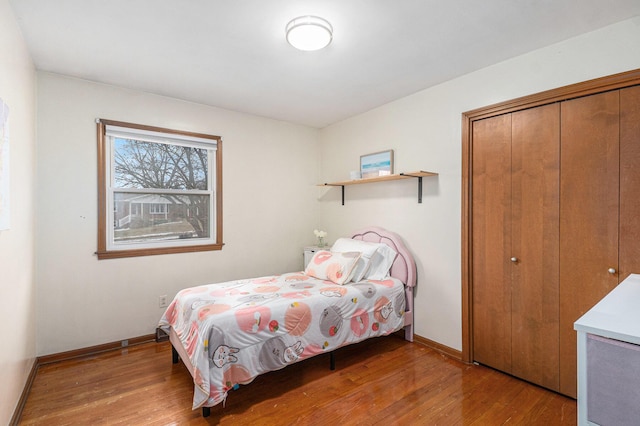 bedroom with a closet, wood finished floors, and baseboards