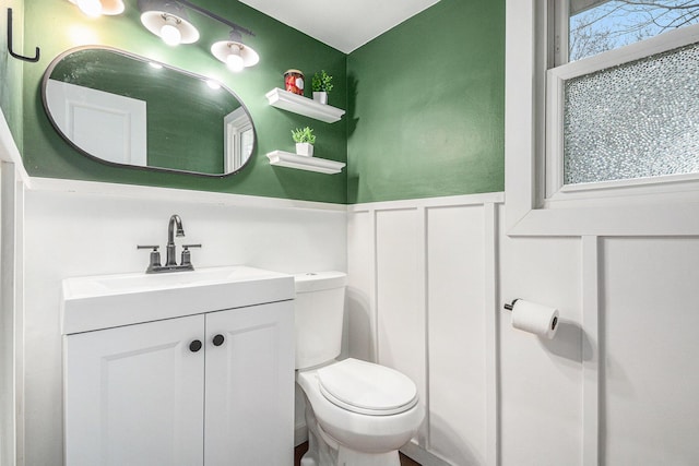 bathroom with wainscoting, vanity, and toilet