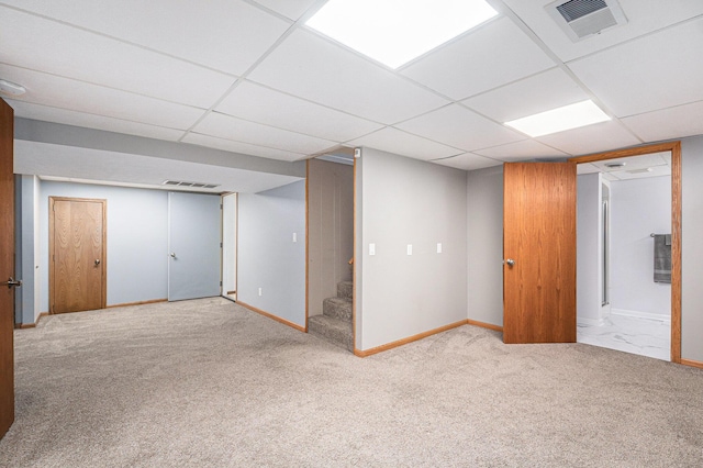 finished below grade area featuring a drop ceiling, stairway, carpet, and visible vents