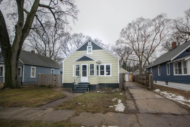 view of front of home with an outbuilding, entry steps, fence, a garage, and driveway