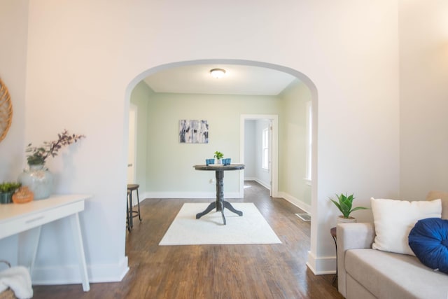 interior space with arched walkways, dark wood-style floors, visible vents, and baseboards