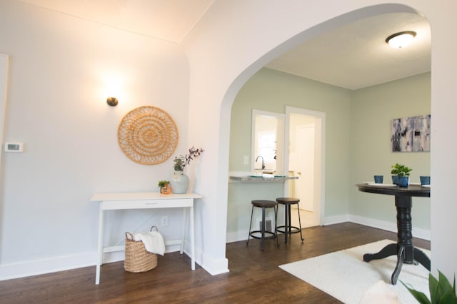 interior space featuring dark wood-style floors, arched walkways, and baseboards