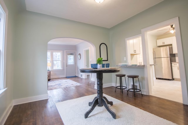 entrance foyer featuring dark wood-type flooring, arched walkways, and baseboards