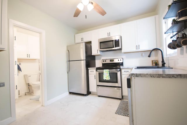 kitchen featuring ceiling fan, a sink, white cabinetry, marble finish floor, and appliances with stainless steel finishes