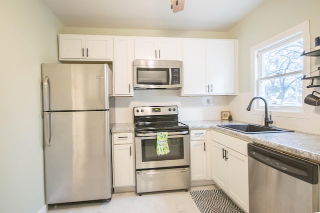 kitchen featuring stainless steel appliances, a sink, and white cabinetry