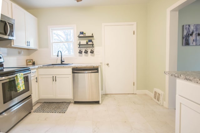 kitchen with marble finish floor, appliances with stainless steel finishes, a sink, and white cabinets