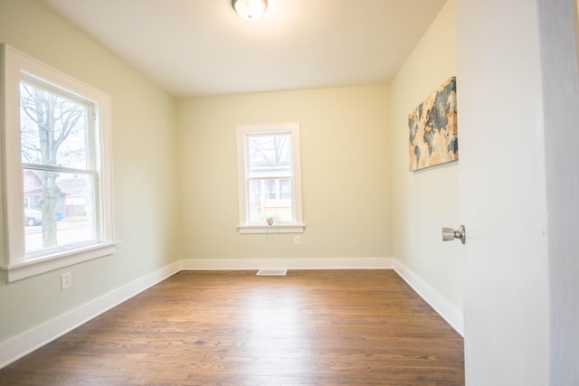 spare room with visible vents, baseboards, and dark wood-style flooring