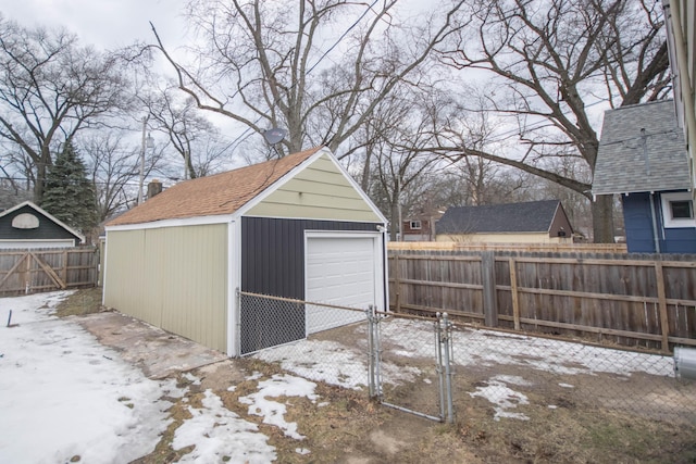 snow covered garage featuring a detached garage and fence