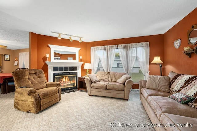 living area with carpet, a textured ceiling, track lighting, and a tiled fireplace