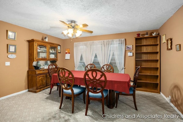 dining room featuring light colored carpet, a textured ceiling, and baseboards