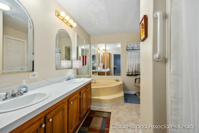 full bathroom with double vanity, a textured ceiling, a sink, and tile patterned floors