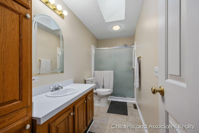 bathroom featuring a skylight, a stall shower, toilet, a textured ceiling, and vanity