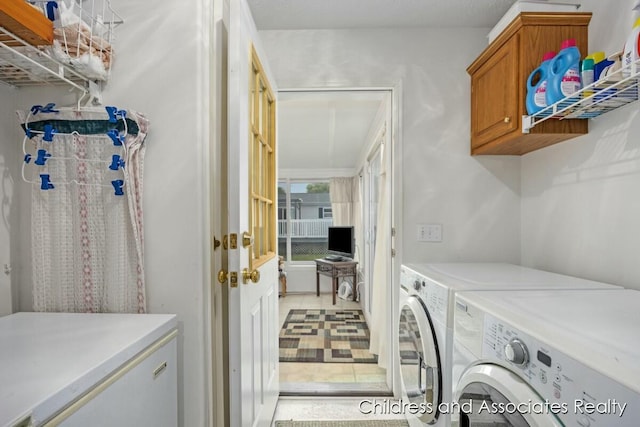 laundry area with cabinet space, light tile patterned floors, and washer and dryer