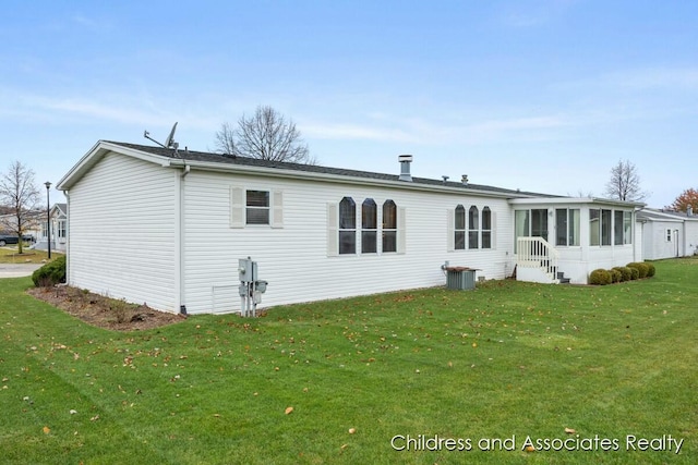 rear view of property featuring a sunroom and a yard