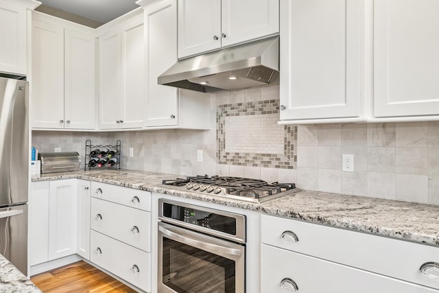 kitchen with tasteful backsplash, white cabinets, light wood-style floors, stainless steel appliances, and under cabinet range hood