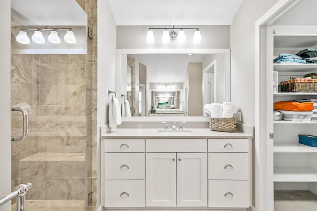 bathroom with a stall shower, a spacious closet, and vanity