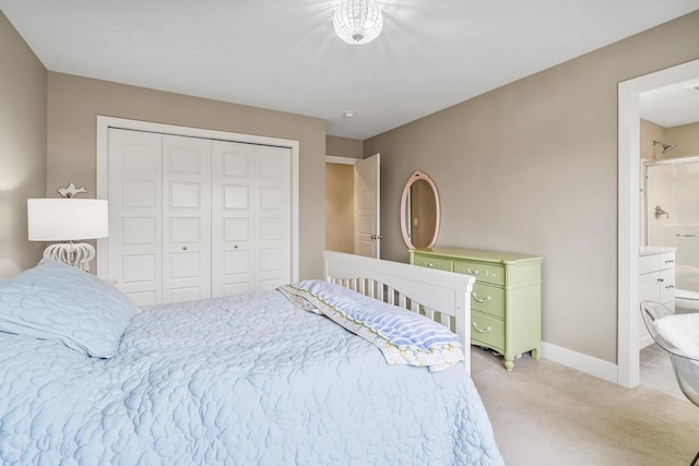 bedroom featuring a closet, light carpet, connected bathroom, and baseboards