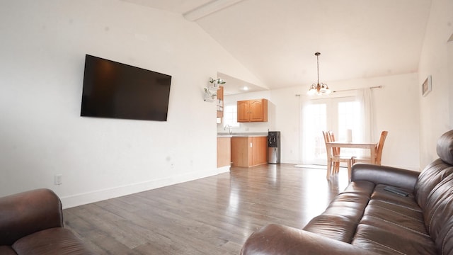 living room featuring a notable chandelier, vaulted ceiling with beams, light wood-style flooring, and baseboards