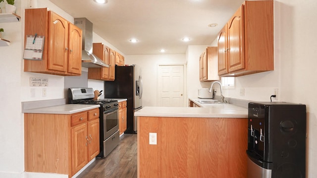 kitchen with dark wood-style flooring, stainless steel appliances, light countertops, a sink, and wall chimney range hood