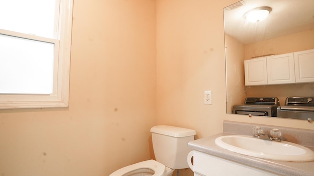 half bathroom featuring washer / clothes dryer, visible vents, vanity, and toilet